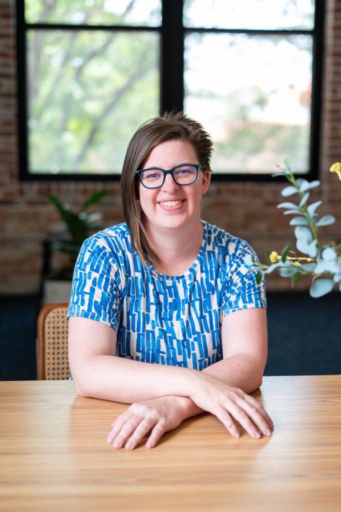 Heidi Lindemann, therapist and counselor, sitting at a table in a bright office with books and soft window light